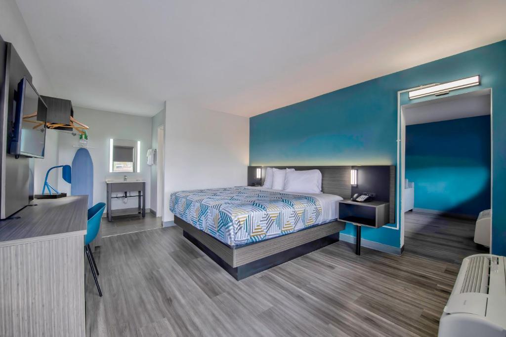 ein Hotelzimmer mit einem Bett und einer blauen Wand in der Unterkunft Studio 6 Jackson MS I 55 in Jackson