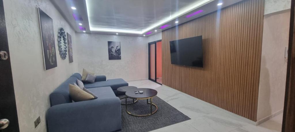 un salon avec un canapé bleu et une télévision dans l'établissement Kech vacations luxury Guest friendly 2 bedroom apartment, à Marrakech
