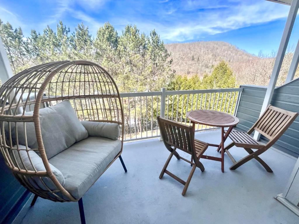 a porch with a swing and two chairs and a table at Condo moderne, escapade vacance, vue sur montagnes in Mont-Tremblant