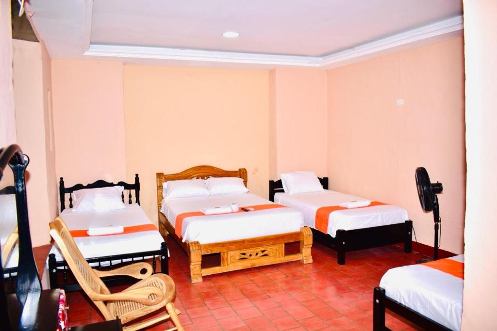 una habitación con 3 camas y una silla. en HOSTAL LA MOMPOSINA, en Mompox