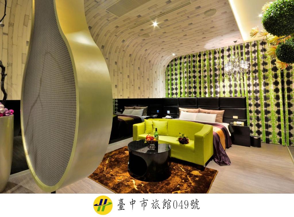 a hotel room with a bed and a yellow couch at Hea Duenn Motel in Taichung