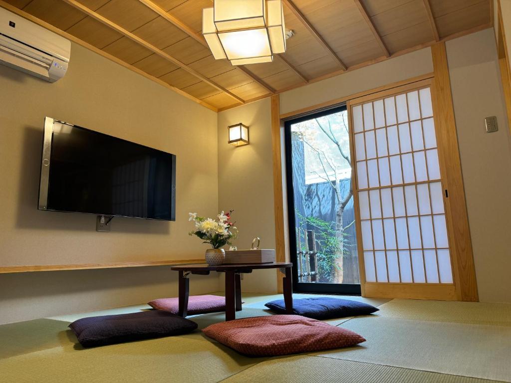 uma sala de estar com televisão e uma mesa com almofadas em 京都駅そばの一棟貸し京町家 suiten shichijo 萃点七条 em Quioto