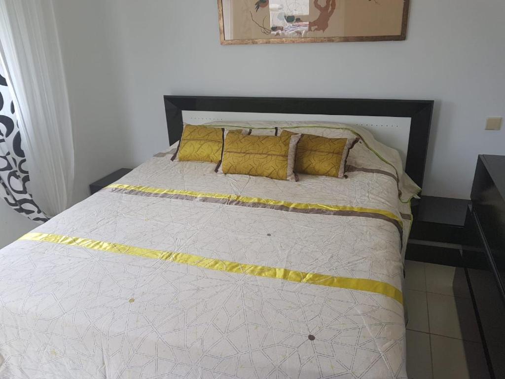 uma cama com almofadas amarelas num quarto em Résidence Al Cudia Smir - Plage Riffiyenne em Fnideq