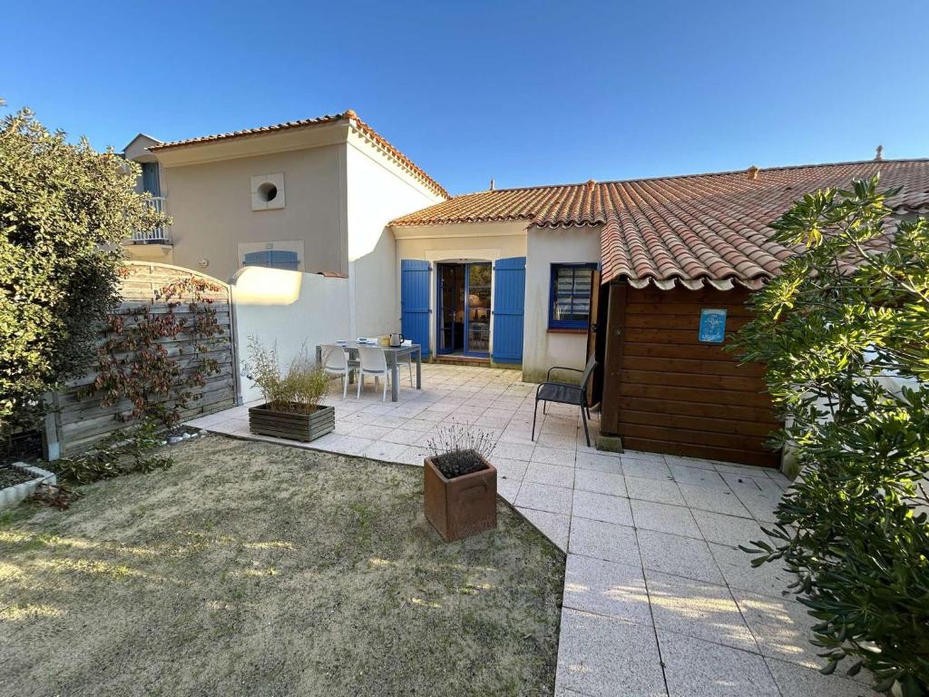Cette maison dispose d'une terrasse avec une table et une clôture. dans l'établissement Petite maison proche de l'océan avec piscine chauffée, jardin privé et parking - St Hilaire de Riez - FR-1-224C-292, à Saint-Hilaire-de-Riez