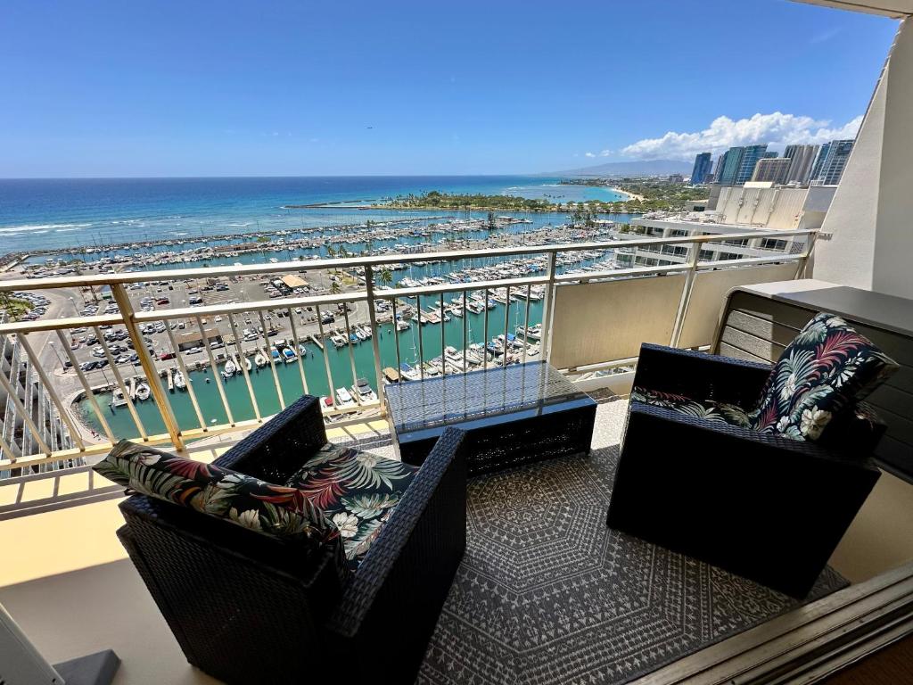 a balcony with two chairs and a view of a beach at Serenity Waikiki ! Luxury Ocean Suite ! in Honolulu