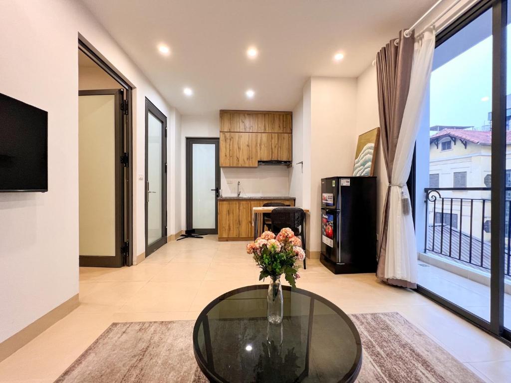 a living room with a glass table and a kitchen at NINE HOUSING 290 Kim Ma in Hanoi