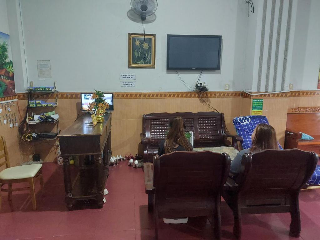 two women sitting in chairs in a room with a tv at Nhà Nghỉ Hương Giang in Xóm Cây Sanh