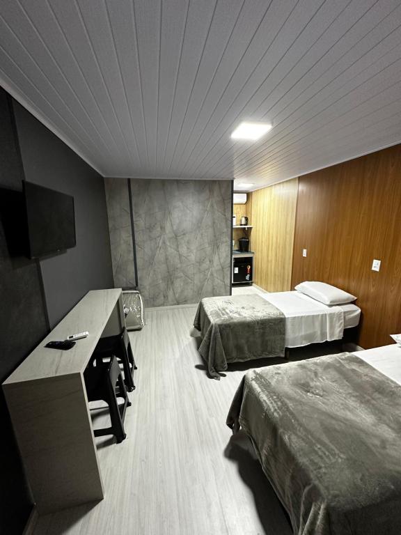 a hotel room with two beds and a desk at Loft Lux 8 in Chapecó