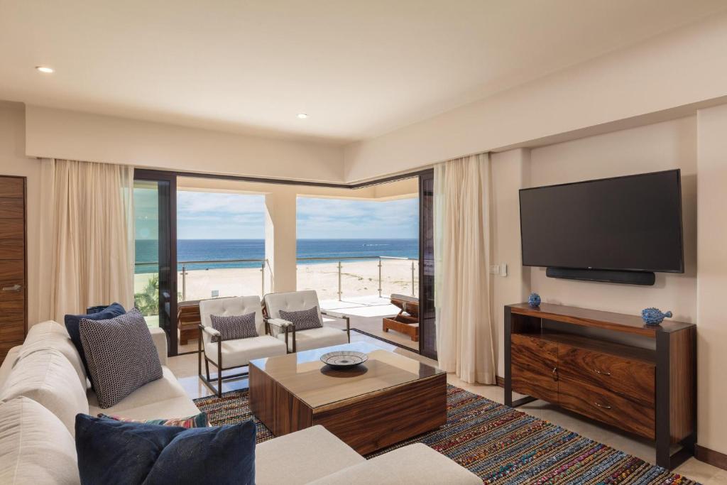 a living room with a couch and a flat screen tv at Beachfront 2 Bdrm Condo in Exclusive Diamante Golf in Cabo San Lucas