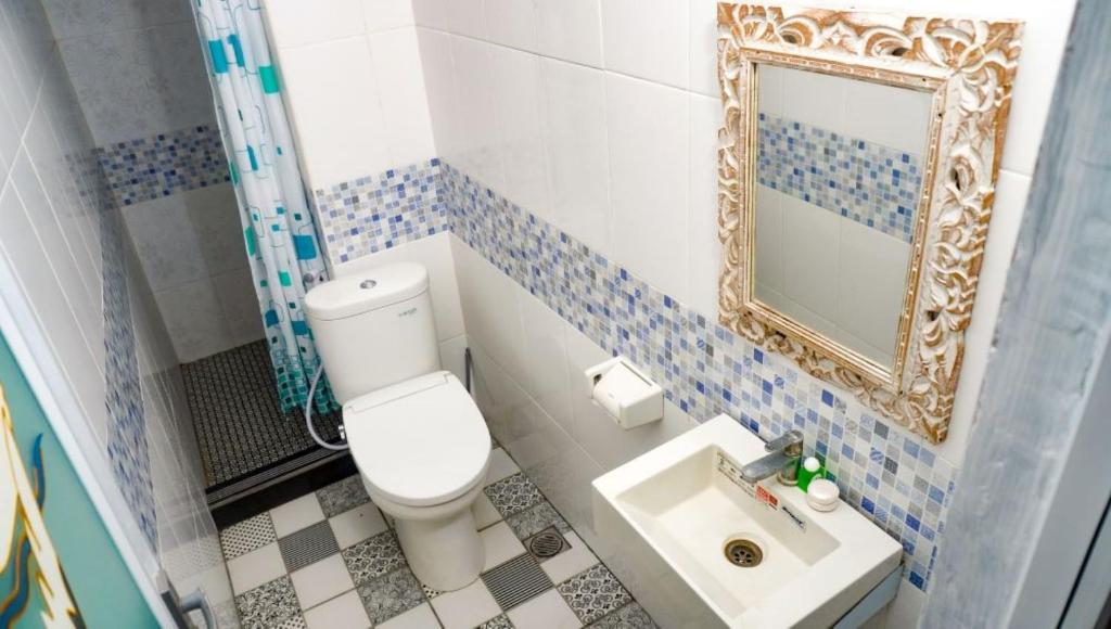 e bagno con servizi igienici, specchio e lavandino. di La Nusa Penida Homestay a Nusa Penida