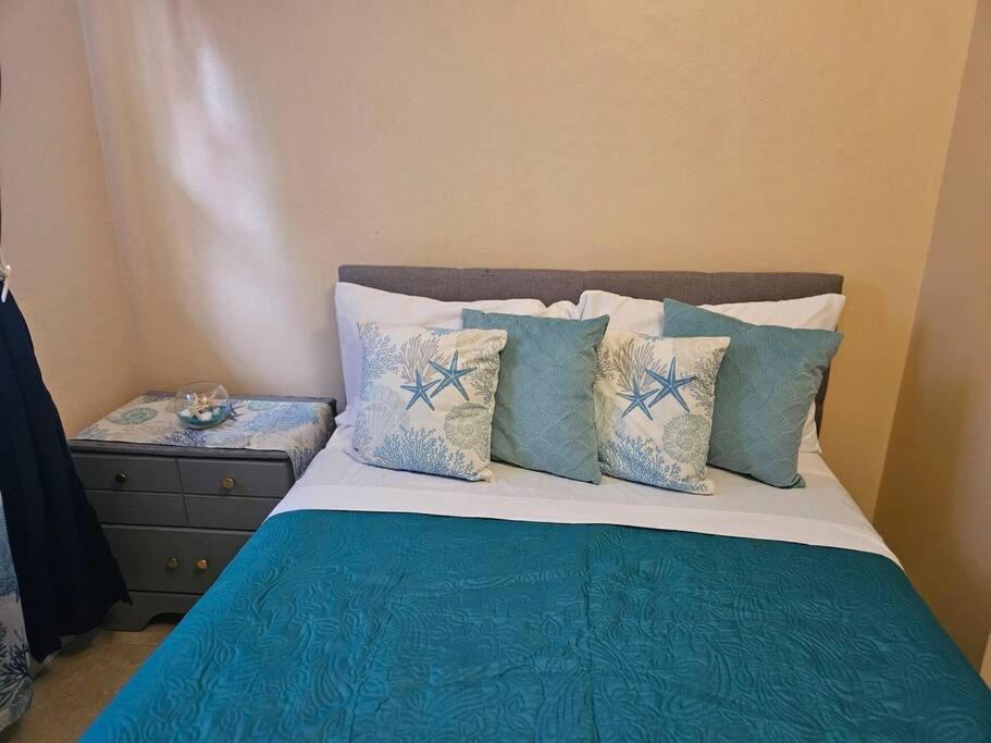 a bedroom with a bed with blue and white pillows at Sarah's Haven in Nassau
