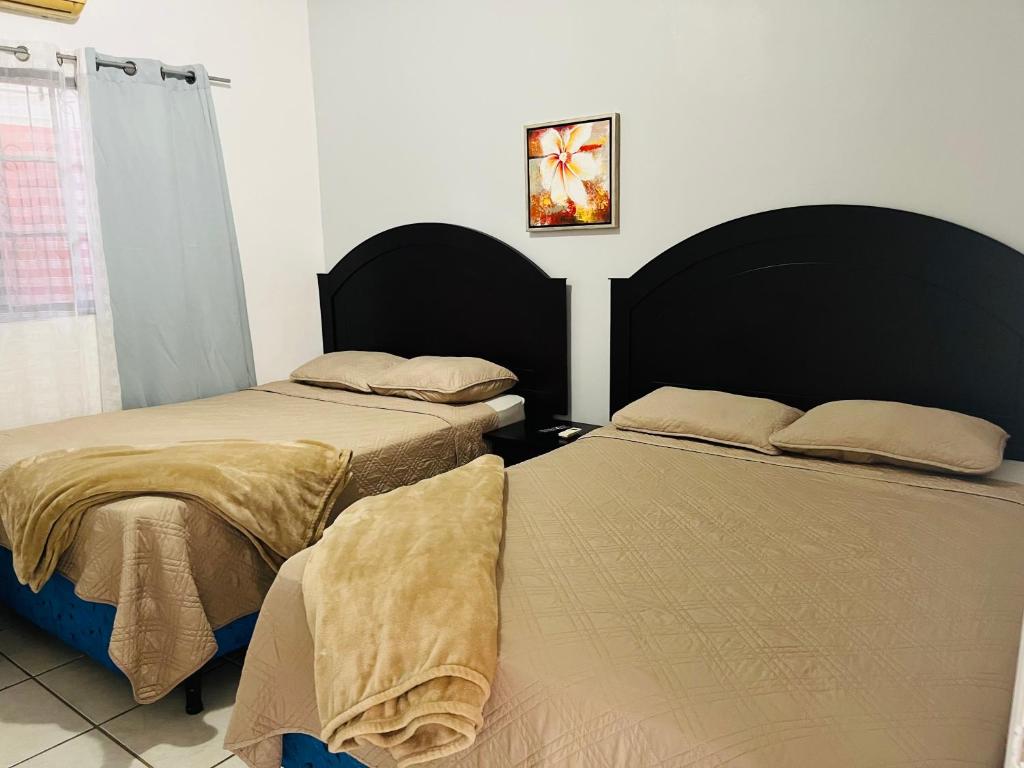 1 dormitorio con 2 camas y ventana en WE Hotel Apartments, en La Lima