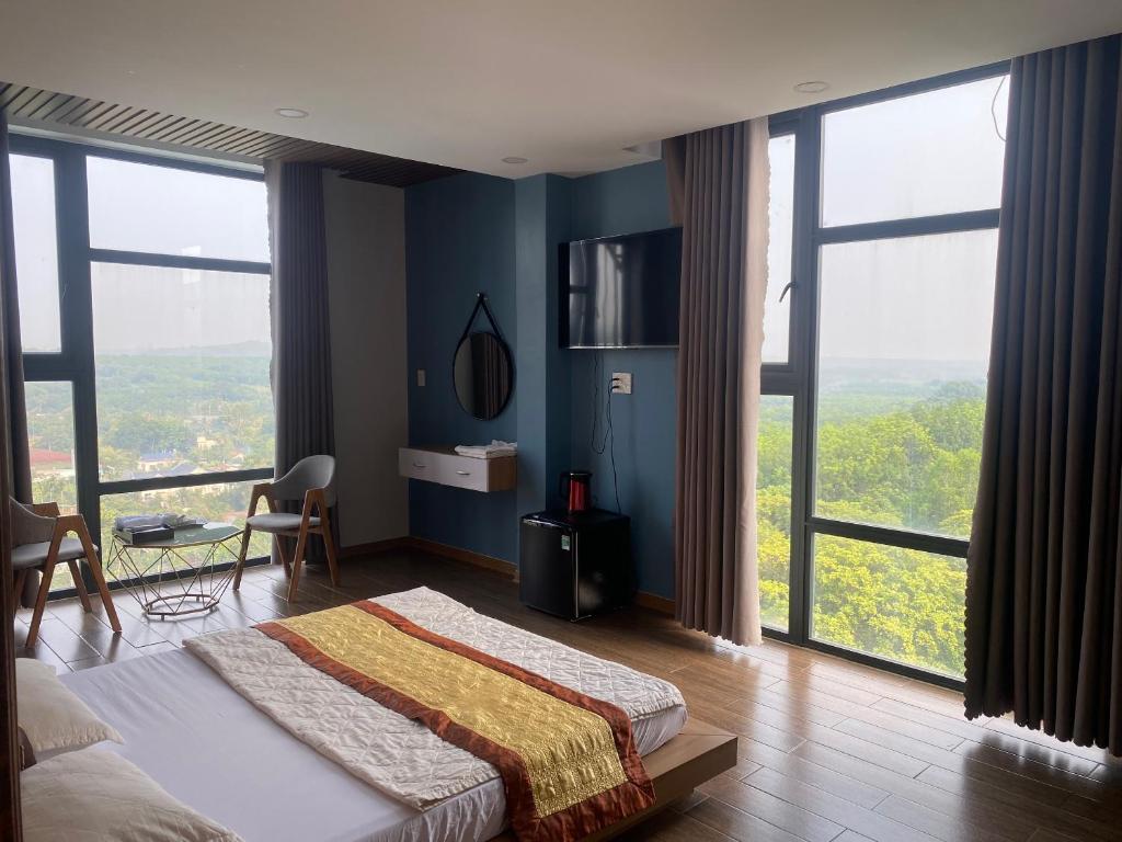 a bedroom with a bed with blue walls and large windows at Hotel Stylish Binh Long in Thanh Bình