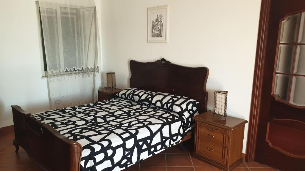 Schlafzimmer mit einem schwarzen und weißen Bett und einem Fenster in der Unterkunft Room in Apartment - Beb apartment Pompeii Rendine in Boscotrecase