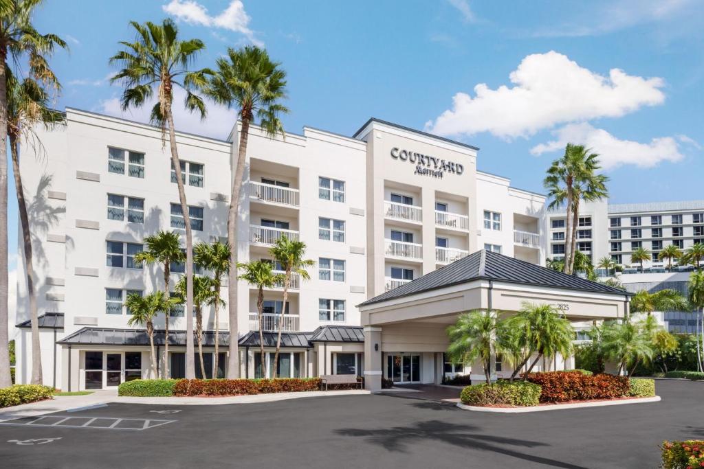 an exterior view of a hotel with palm trees at Courtyard by Marriott Miami Aventura Mall in Aventura