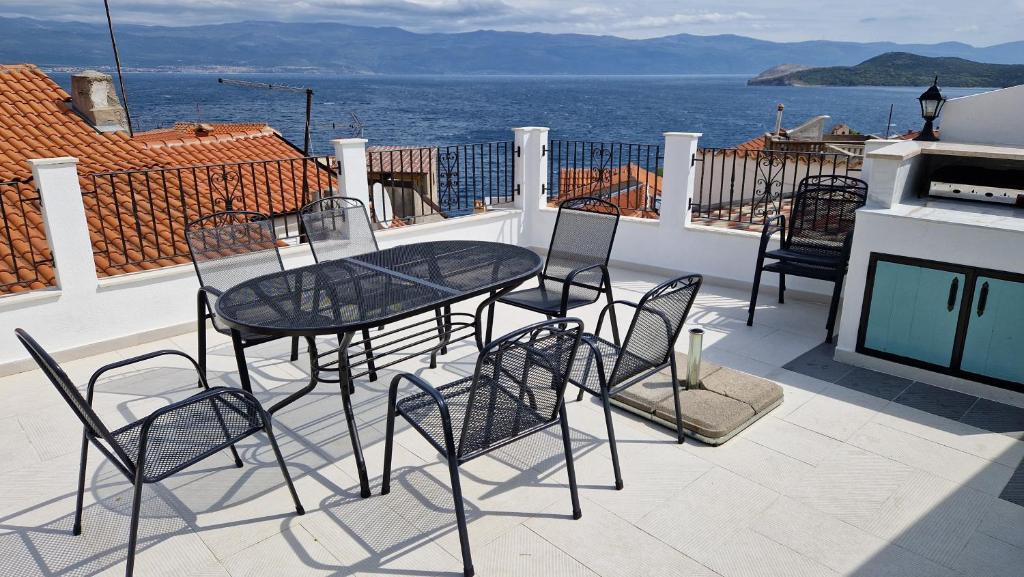 a patio with a table and chairs on a balcony at Magdalena in Vrbnik
