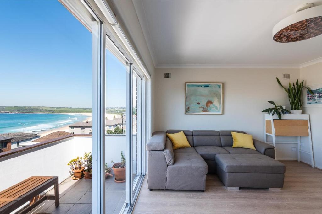 uma sala de estar com um sofá e vista para o oceano em Stunning Maroubra Beachview Apt with Parking em Sidney