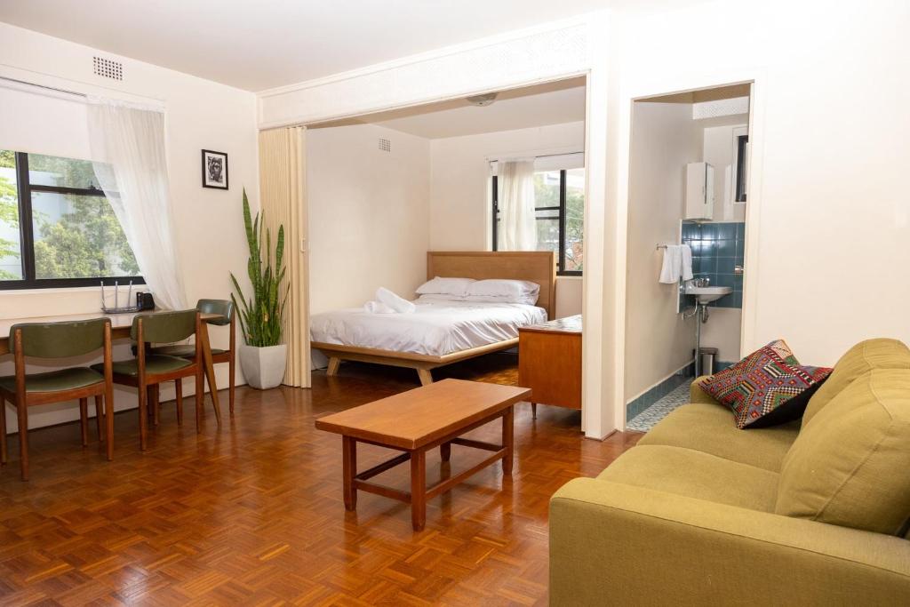 uma sala de estar com um sofá, uma cama e uma mesa em Light-Filled Paddington Studio with Parking em Sydney