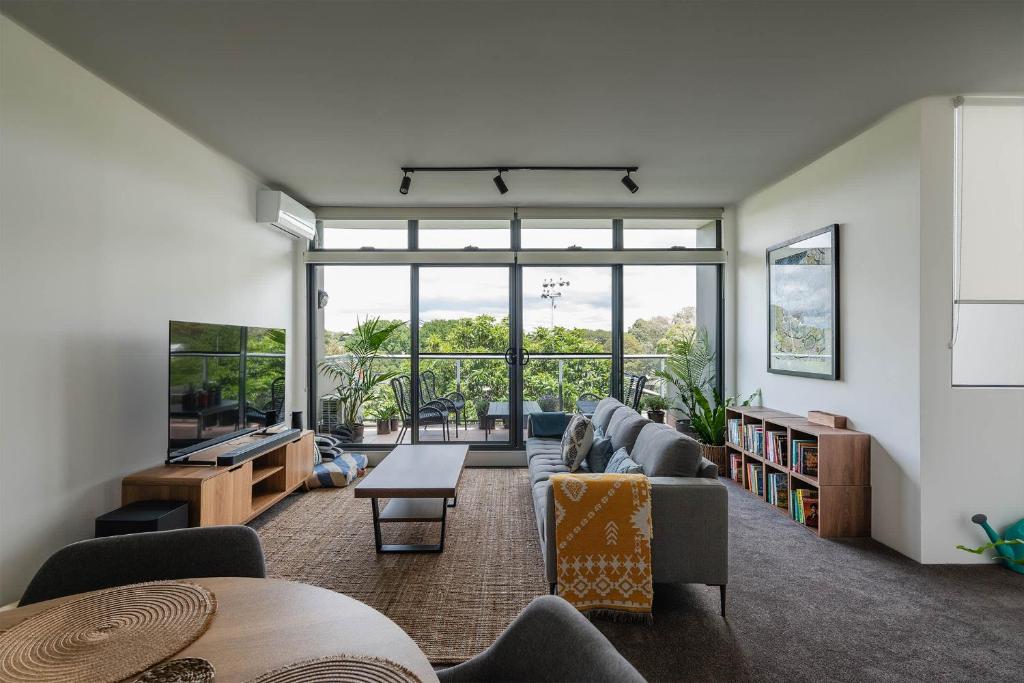 a living room filled with furniture and a large window at Treetops Camperdown Inner City Bliss w Parking in Sydney