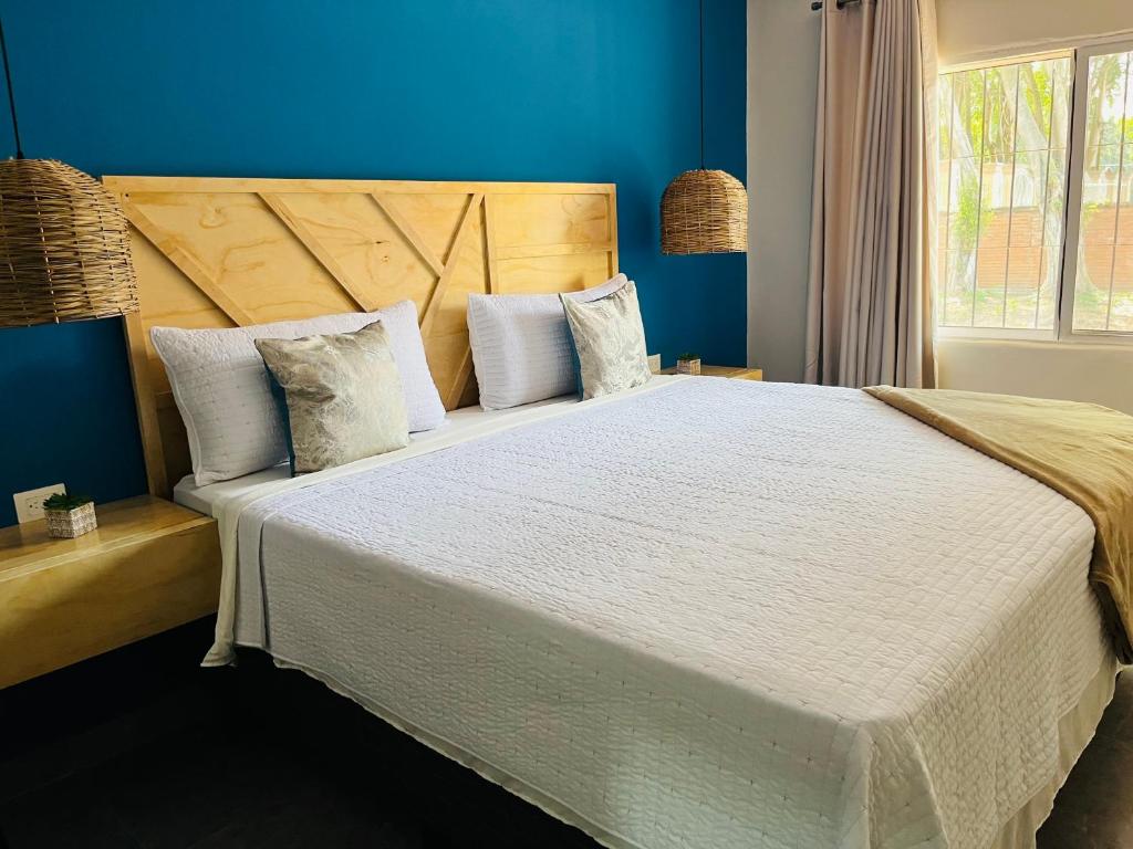 a bedroom with a large bed with blue walls at WE Hotel, La Lima in La Lima