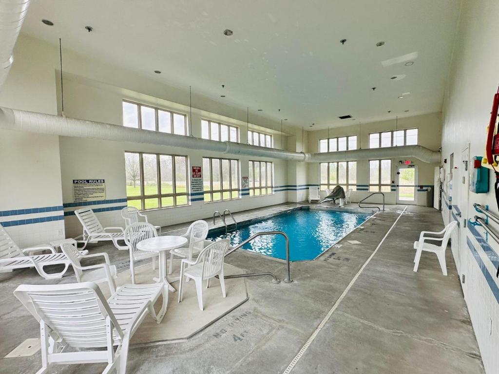 einen großen Pool mit weißen Stühlen sowie einem Tisch und Stühlen in der Unterkunft Quality Inn & Suites Rockport - Owensboro North in Rockport