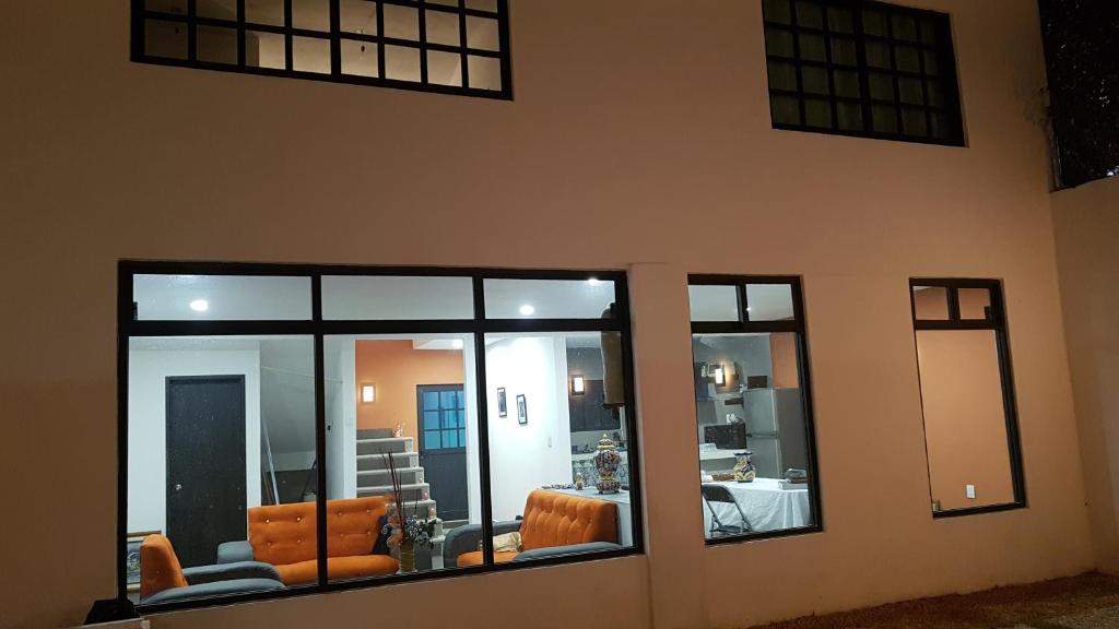 una sala de estar con ventanas de cristal y sillas naranjas. en La morada naranja Tepotzotlán, en Tepotzotlán