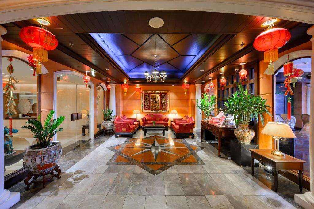 A richly decorated hotel lobby lounge with red seating, plants, and Chinese-inspired details.