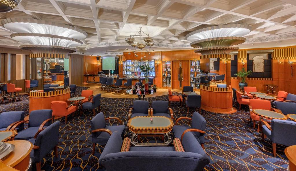 A grand central lounge with grouped seating, decorative counters, and a bar in the distance.