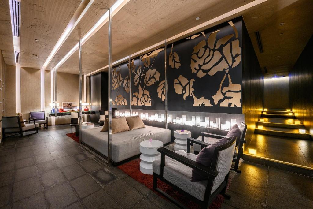 A softly lit hotel lounge with upholstered seating and decorative screens.