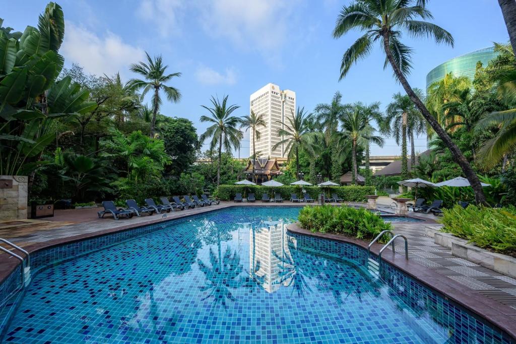 The pool is framed by tropical planting, loungers and the hotel tower.