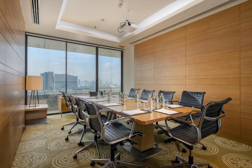 A private boardroom with a projector, conference table, and skyline windows.