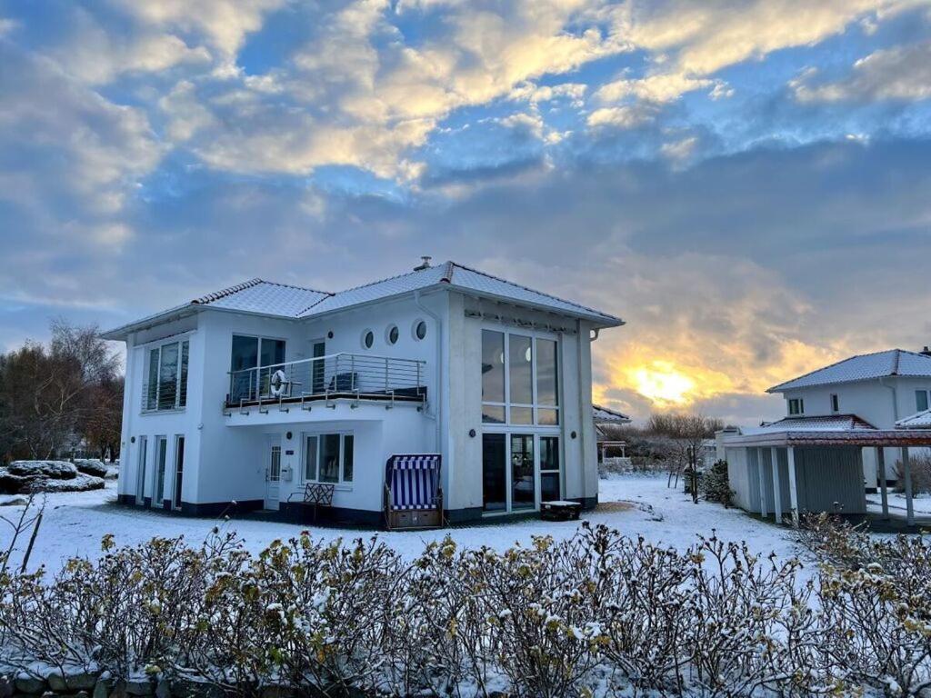 a white house in the snow with the sunset in the background at To"n Lüchtfüer Comfortable holiday residence in Dwarsdorf