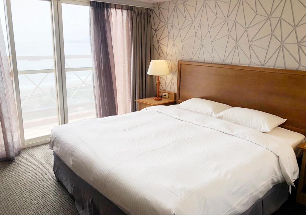a large bed in a hotel room with a large window at Beach Resort Green Bay in Wanli District