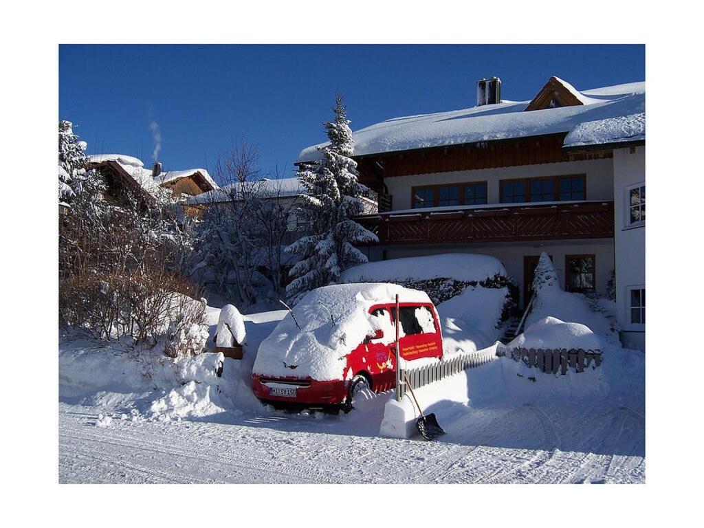 a red van covered in snow in front of a house at Kreuzwiesen Modern retreat in Missen-Wilhams