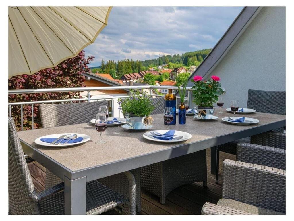 a table with plates and wine glasses on a balcony at Romantic maisonette in Schonach