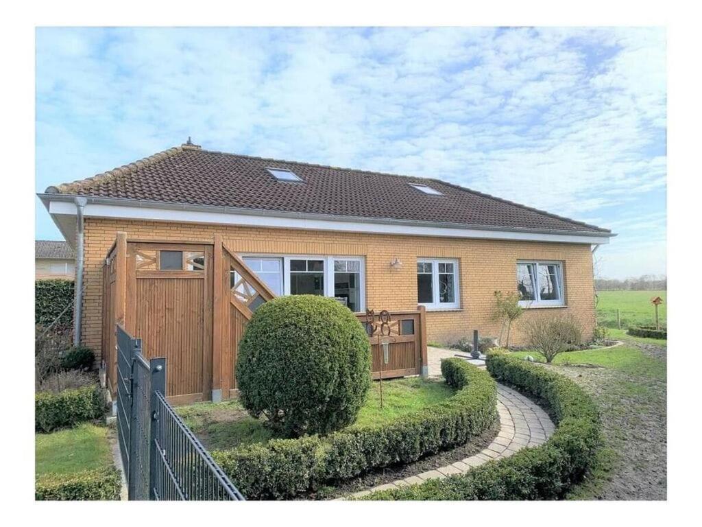 una casa con un cancello in legno e una recinzione di Ostfriesland to huus a Hinte