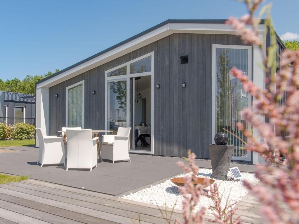 Casa modular con patio y sillas blancas en Chalet with decorative fireplace on a holiday park en Wemeldinge