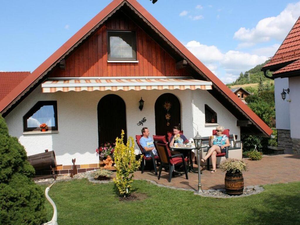 a group of people sitting at a table in front of a house at in the Oertel holiday home 