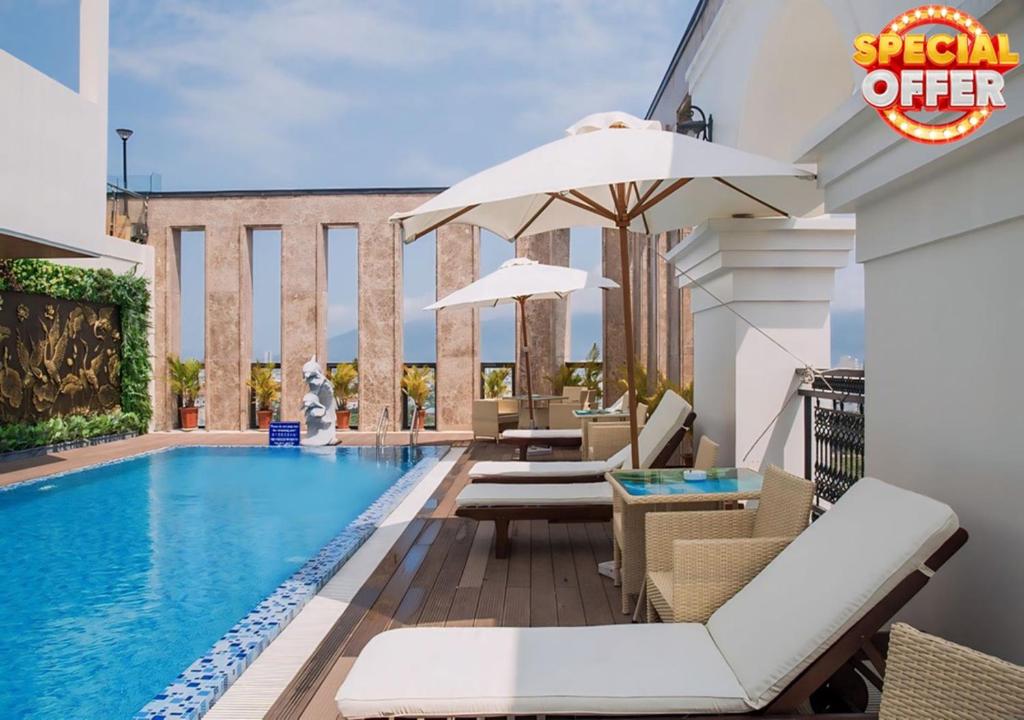 a pool with chairs and an umbrella next to a building at Danaciti Hotel in Danang