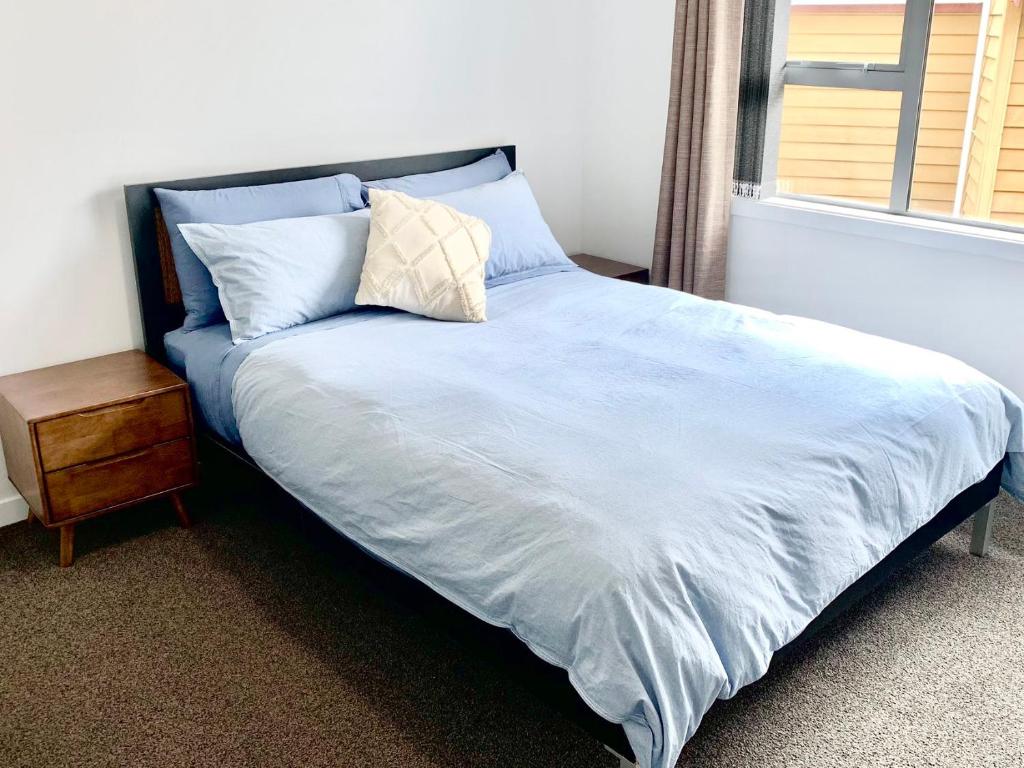 um quarto com uma cama com uma almofada e uma janela em Comfy & Sunny home in Wellington em Wellington