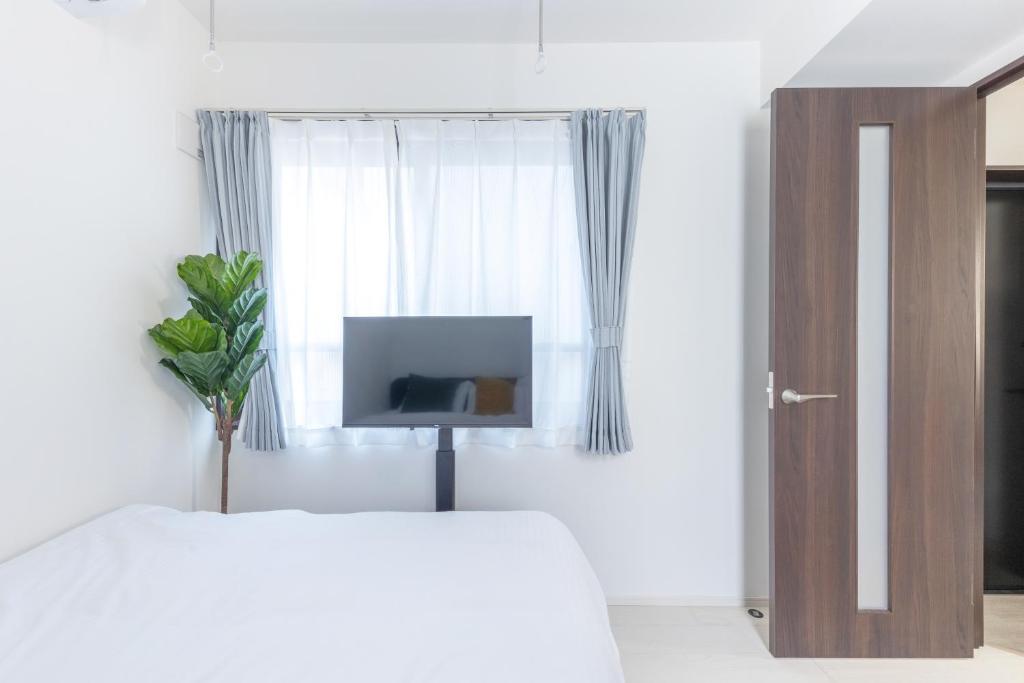 biała sypialnia z łóżkiem i telewizorem w obiekcie 67Hotel Koenji Tokyo w Tokio