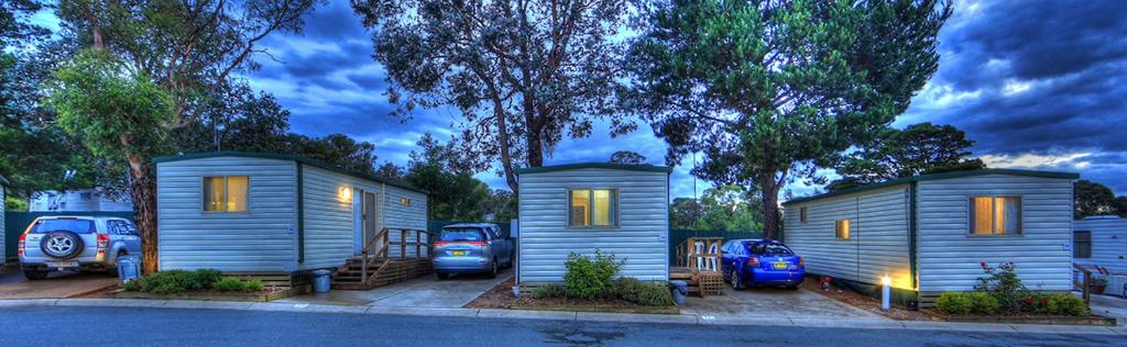 dos pequeñas casas en un estacionamiento con autos aparcados en Governors Hill Carapark, en Goulburn