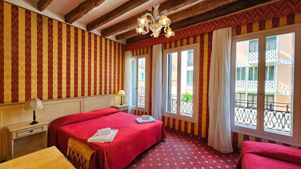 um quarto com uma cama vermelha e 2 janelas em Messner Palace em Veneza