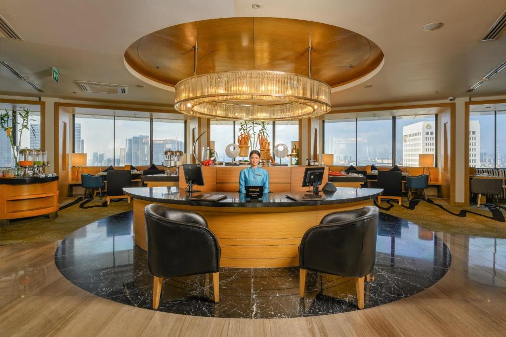 A staffed circular reception bar in a bright upper-level lounge.
