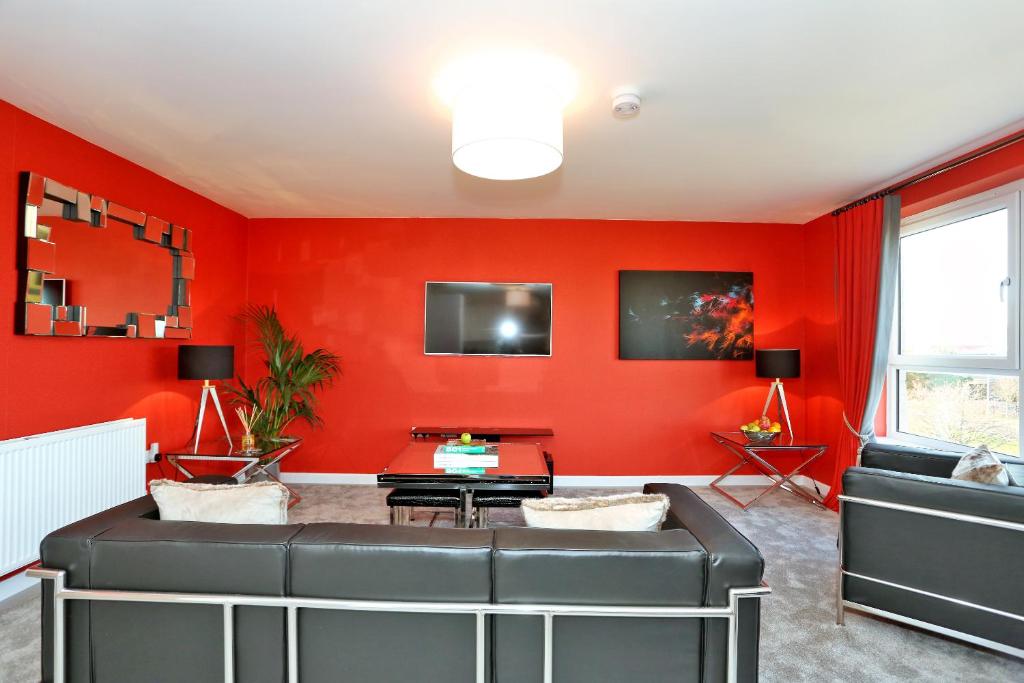a living room with red walls and a black leather couch at Fabulous Aberdeen Home near the city centre in Dyce