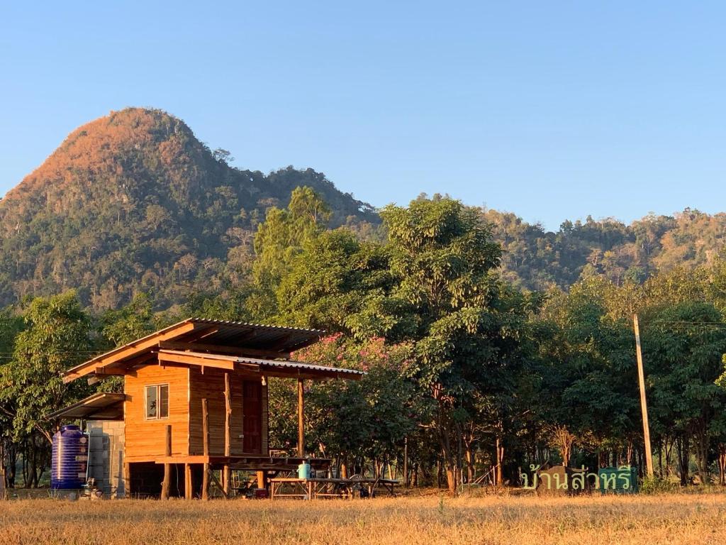 a small wooden house in front of a mountain at บ้านส่าหรีโฮมสเตย์ in Lan Sak