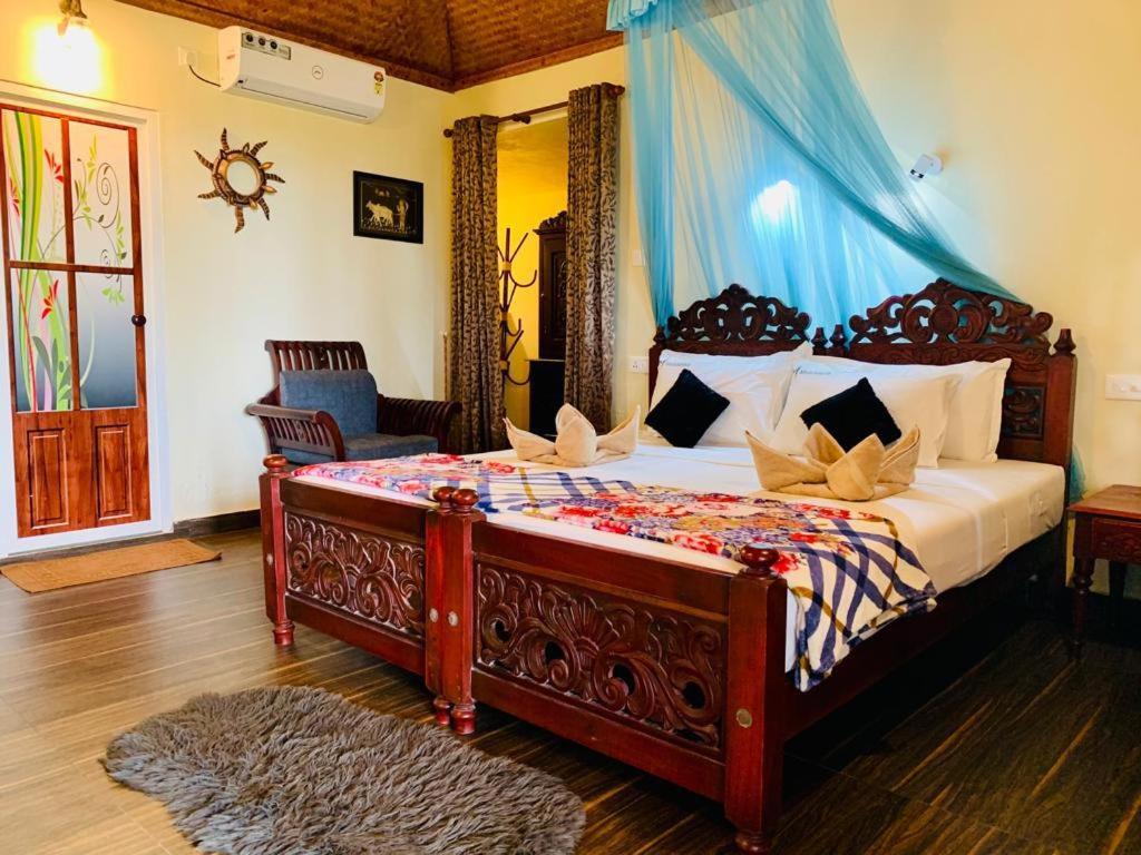 a bedroom with a large bed with a blue canopy at Maadathil Beach Resort in Varkala