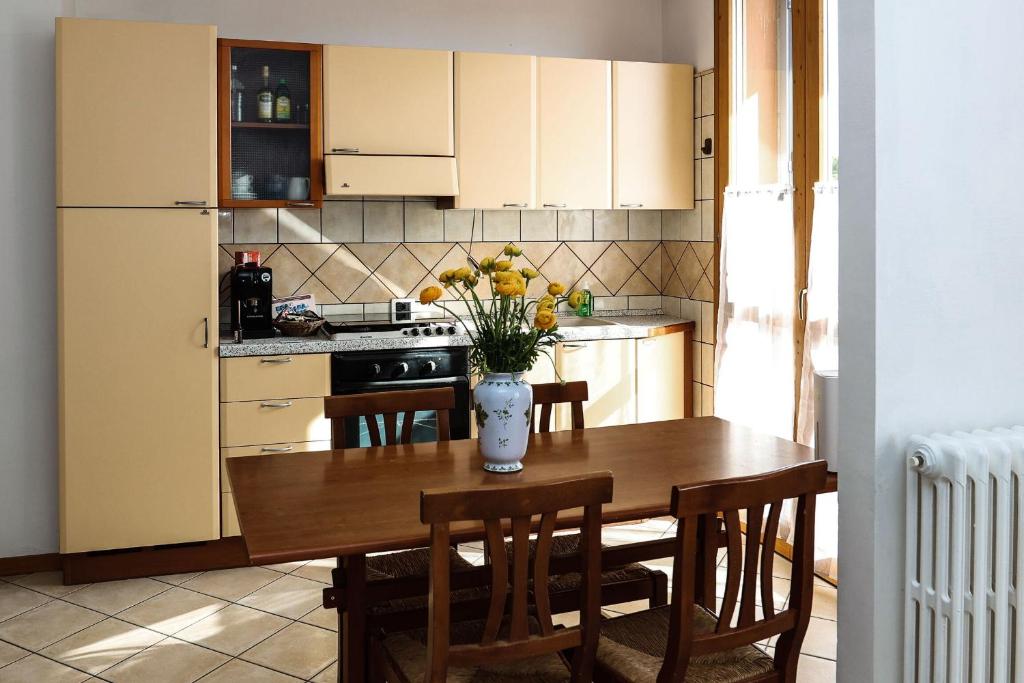 a kitchen with a wooden table with a vase of flowers on it at Confortevole monolocale faentino con terrazza in Faenza
