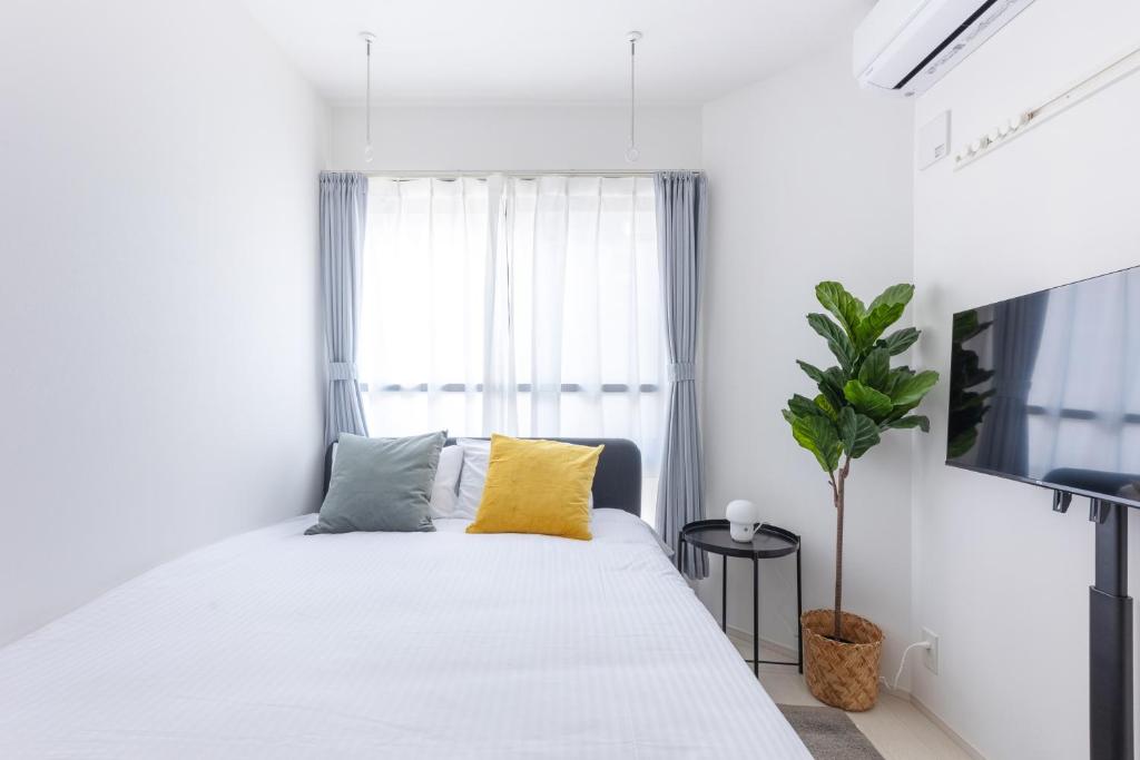 a white bedroom with a large bed with yellow pillows at APB高円寺 in Tokyo