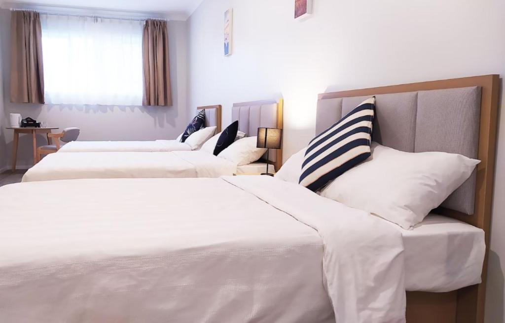 um quarto de hotel com três camas e uma janela em AWA Hotel em Rotorua
